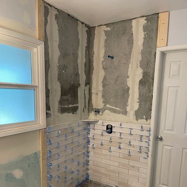 Partial bathroom wall tiling in progress with white subway tiles.
