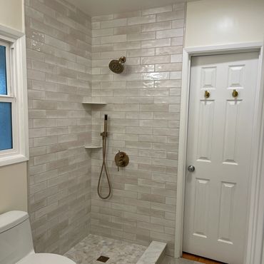 Modern beige tiled walk-in shower with gold fixtures.