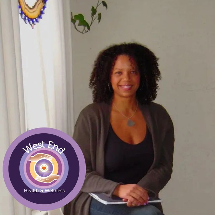Clare Wilson, Holistic Life Coach and Massage Therapist sitting on a chair smiling.