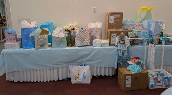 A table filled with baby shower gifts wrapped in pastel and blue.