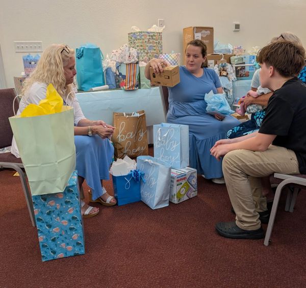 Group opening baby gifts at a gathering.