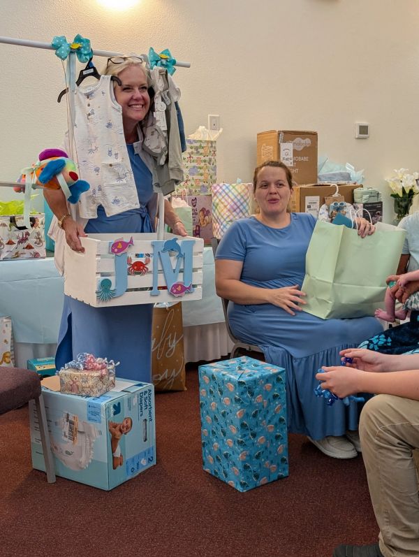 Two women at a baby shower with gifts and decorations.