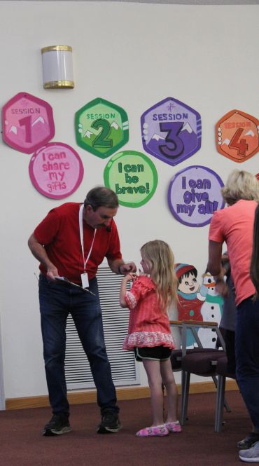 Man and child interacting in a room with colorful session signs on the wall.