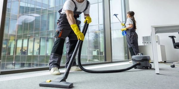 Two janitors cleaning an office floor and window.