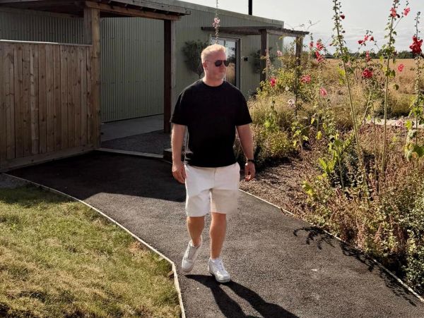 Man walking on a garden path in the sun.