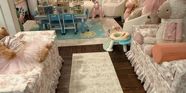 A cozy, pastel-themed children's playroom with plush toys and small furniture.