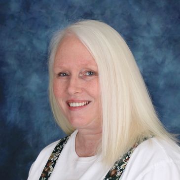 Smiling woman with long white hair against a blue background.