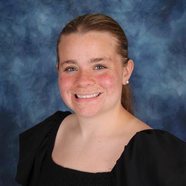 Young woman smiling in a portrait with a blue backdrop.
