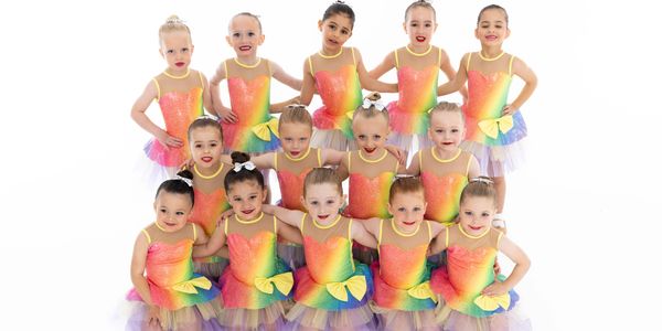 Young girls in colorful dance costumes posing together.