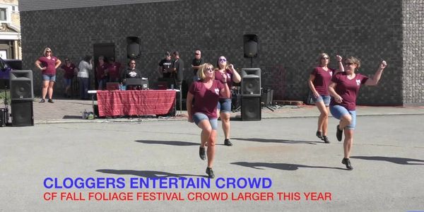 Women cloggers perform energetically at fall festival.