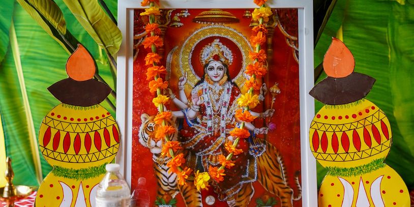 Decorated photo of a Hindu goddess with tiger and floral garland.