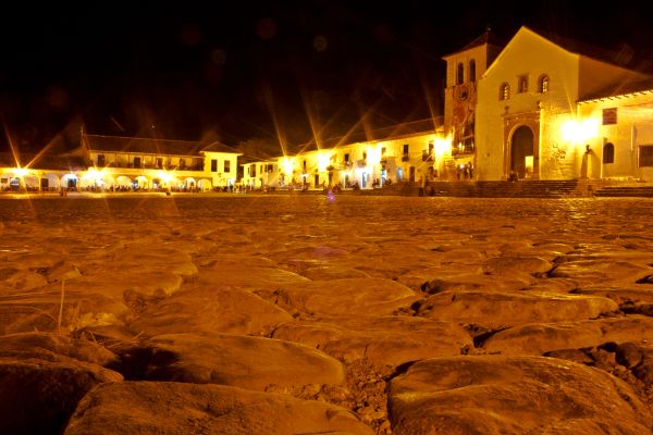 Plaza empedrada iluminada por la noche.