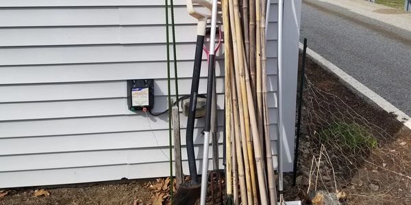 Picture that shows tools being stored leaning against building and improper chicken wire fencing