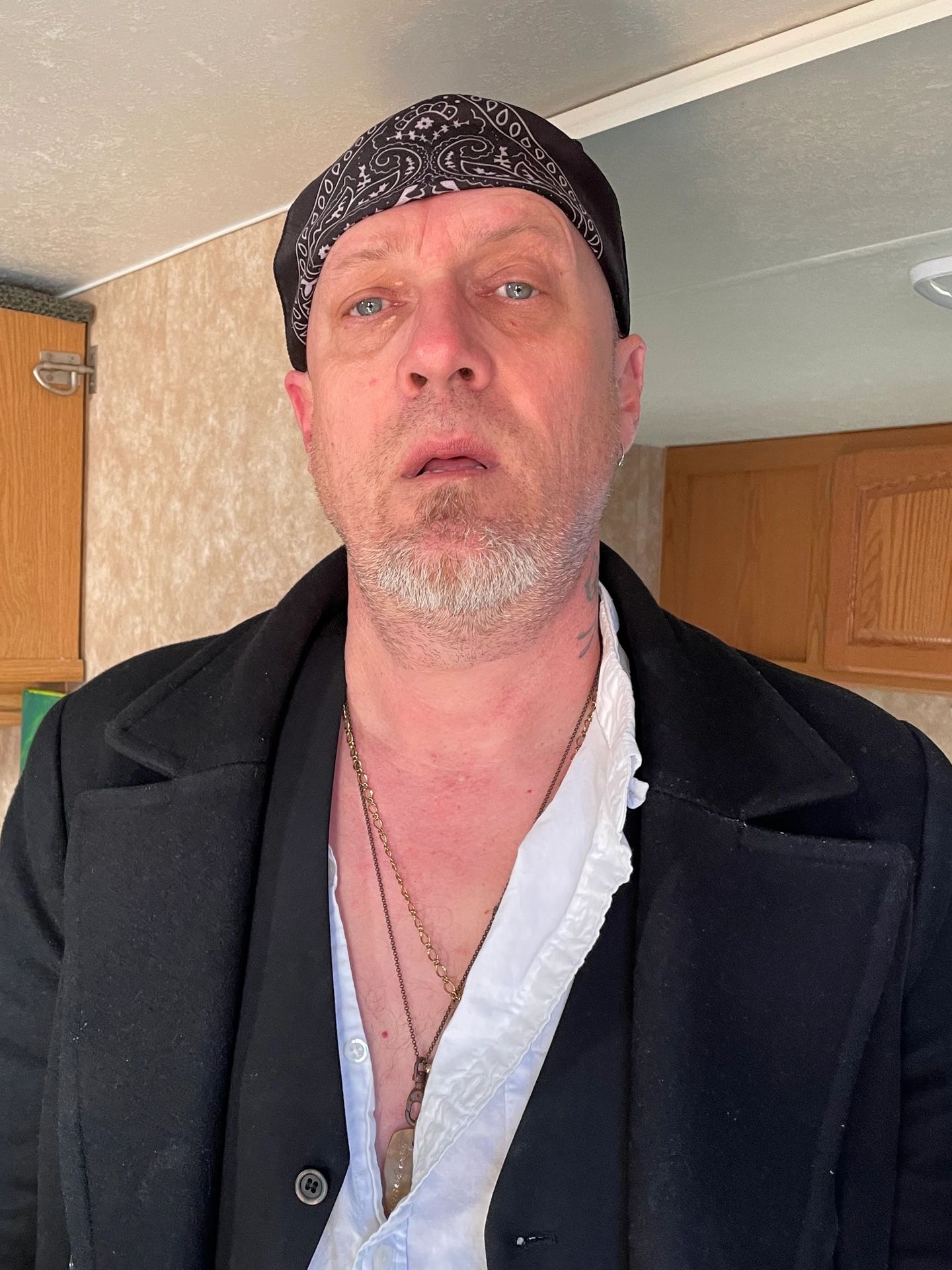 Man with blue eyes wearing a black bandana and coat.