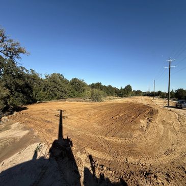 Clear land with dirt and trees under a blue sky.