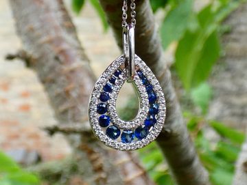 Close-up of a sapphire and diamond pendant hanging from a chain.