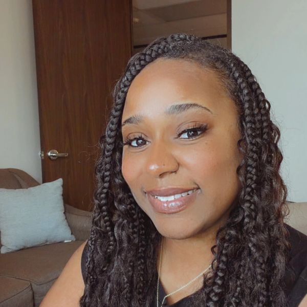 Smiling woman with braided hair in a cozy room.