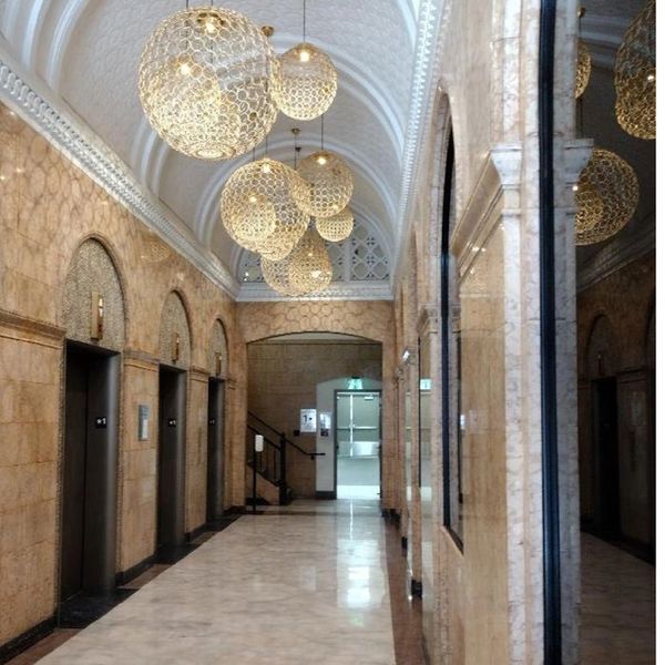 Luxurious marble hallway with ornate chandeliers and arched windows.