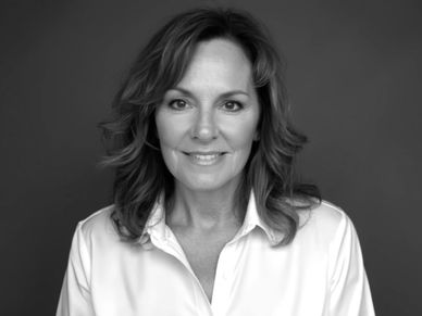Black and white portrait of a smiling woman in a white shirt.