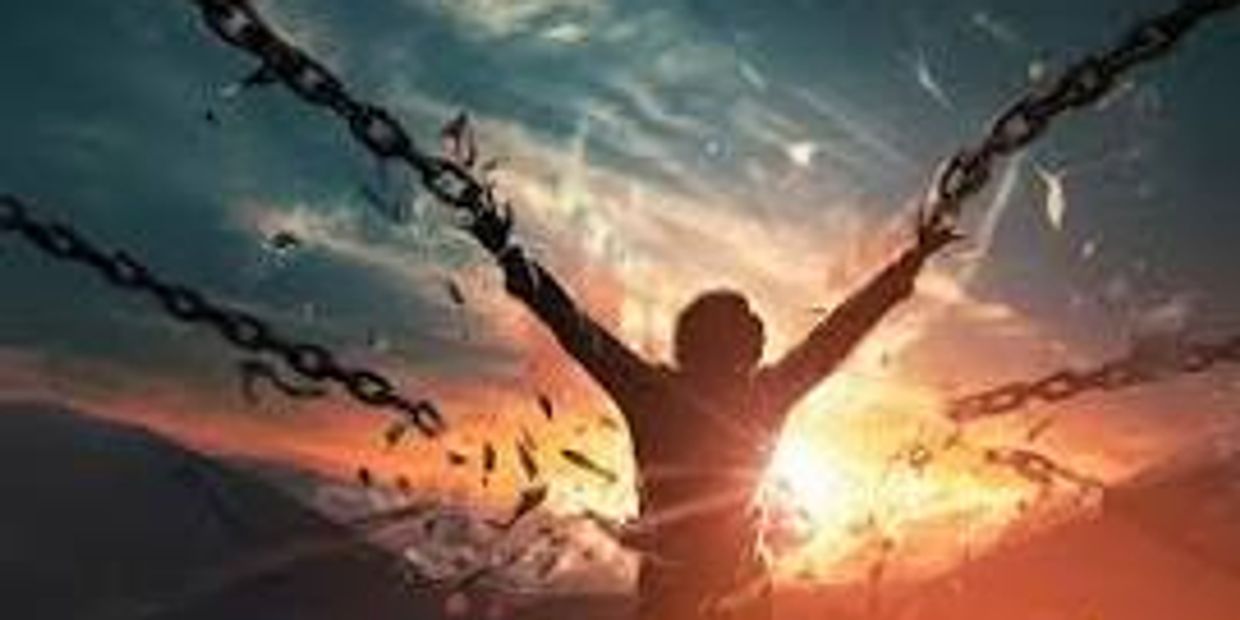 Silhouette breaking chains against a dramatic sunset sky.