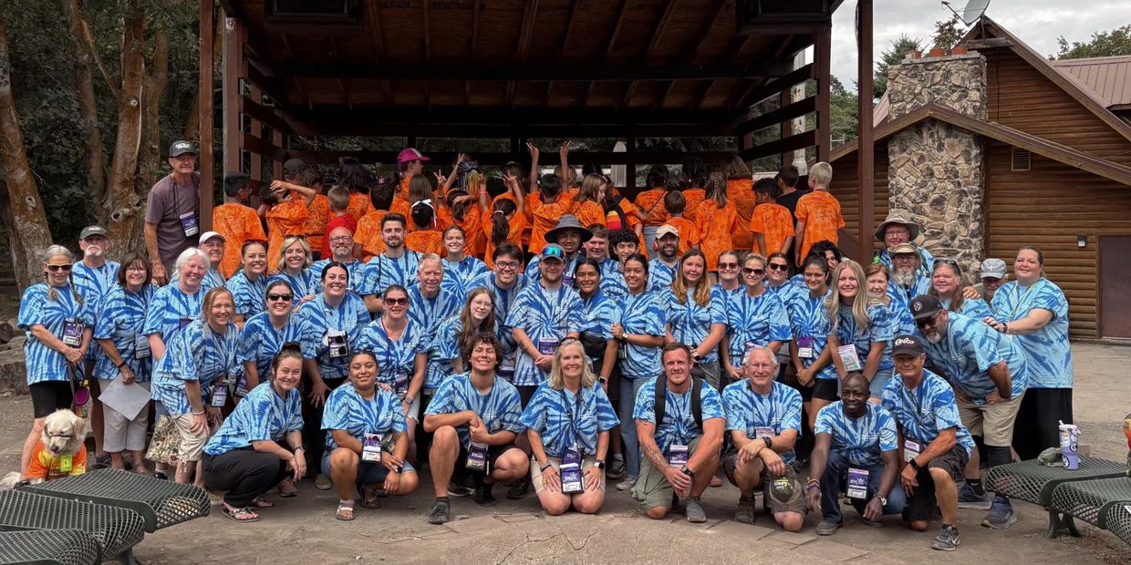 Large group of people in matching blue and orange shirts posing at Prince Theater outdoors.