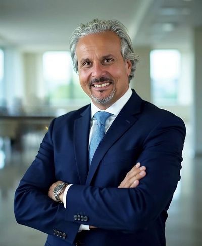 Smiling man in a blue suit with arms crossed.