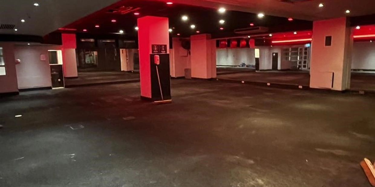 Empty gym floor awaiting demolition with damage to ceiling.