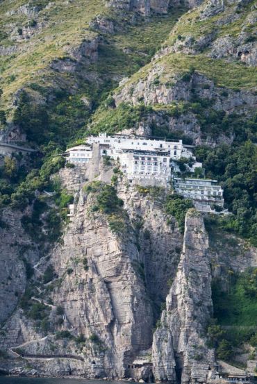 White building perched atop rocky mountain cliffs.