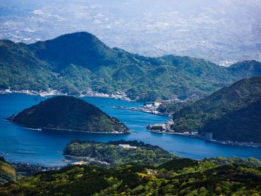 A scenic view of a bay surrounded by green hills and small islands.