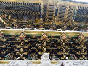 Intricately carved and colorful wooden ceiling beams of a traditional temple.