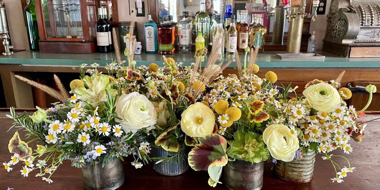 Floral arrangements in antique metal vases. Vintage bar in the background at Triple S Ranch Napa. 
