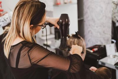 Hair stylist blow drying a ladies hair.