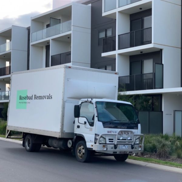 White removal truck parked near modern apartment building.