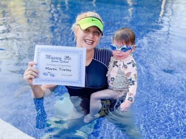 Woman and child in pool holding a swimming certificate.