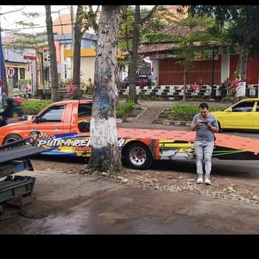 A man standing next to a colorful flatbed truck in a street setting.