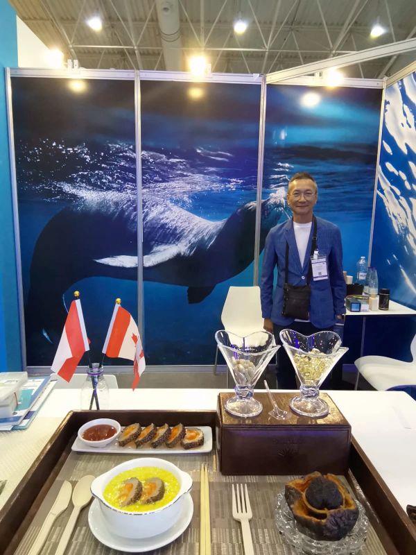 Man standing at marine-themed exhibition booth with food display.