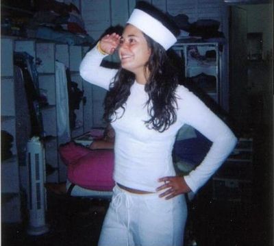 Woman in white outfit saluting indoors.