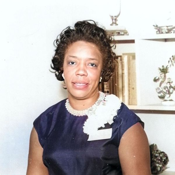 Portrait of a woman in a dark dress with pearl necklace.