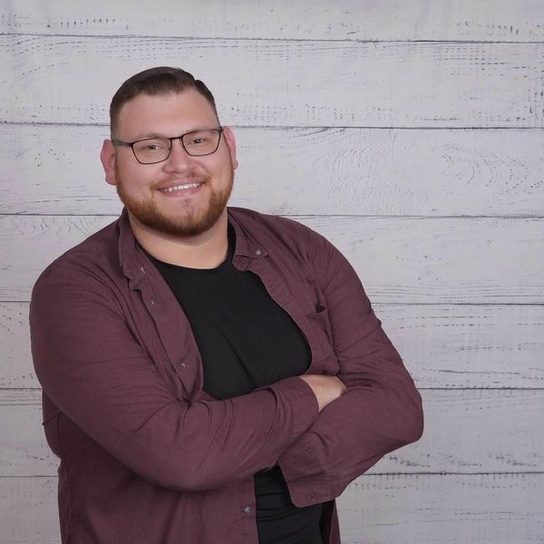 Smiling man with glasses in a casual shirt.