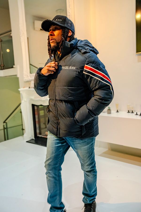 Man wearing a Hazel Jean jacket and cap indoors.