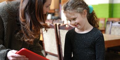 A woman and a young girl share a joyful moment indoors.