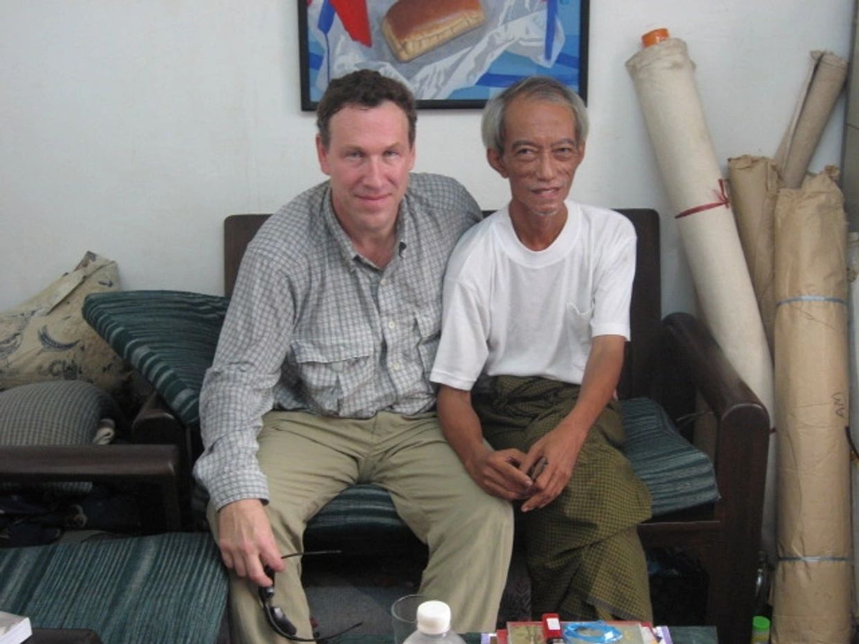 Two men sitting closely on a couch in a casual indoor setting.