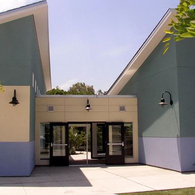 Modern building entrance with open double glass doors and wall-mounted lights.