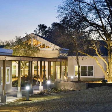 Modern building with illuminated walkway and trees at dusk.