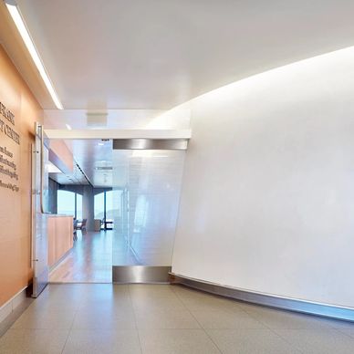 Modern hospital hallway with glass doors and clean design.
