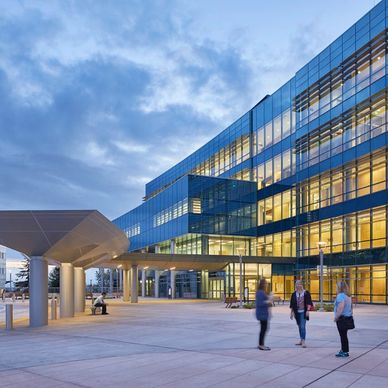 Modern glass building with people outside at dusk.