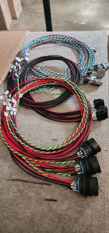 Coiled multicolored electrical wiring harnesses on a surface.