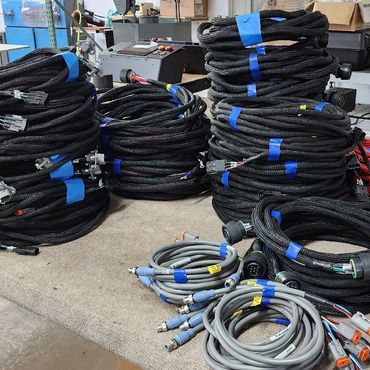 Stacks of coiled cables organized with blue tape on a table.