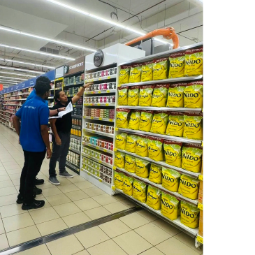 Three men in a supermarket aisle looking at products.
