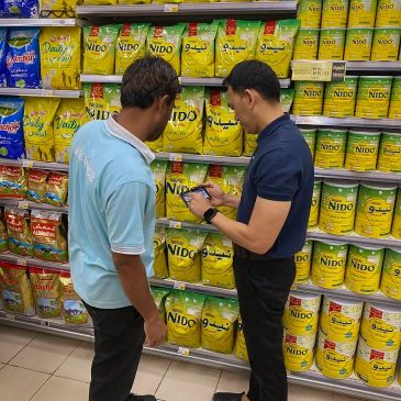 Two men inspecting Nido milk powder packages in a store aisle.